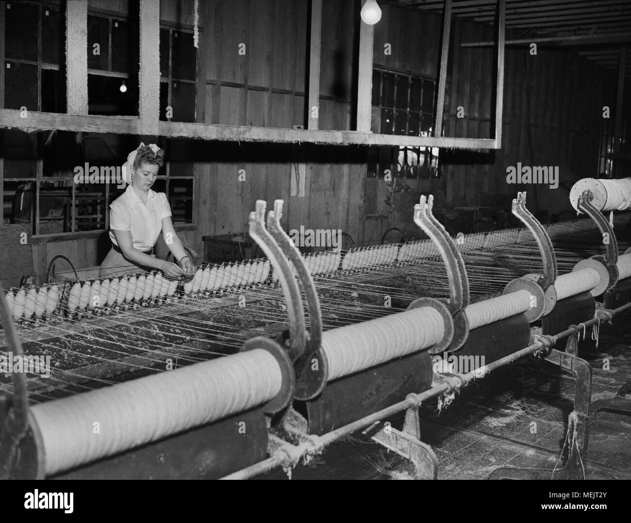 A worker watches an early industrial plastic manufacturing process in a ...