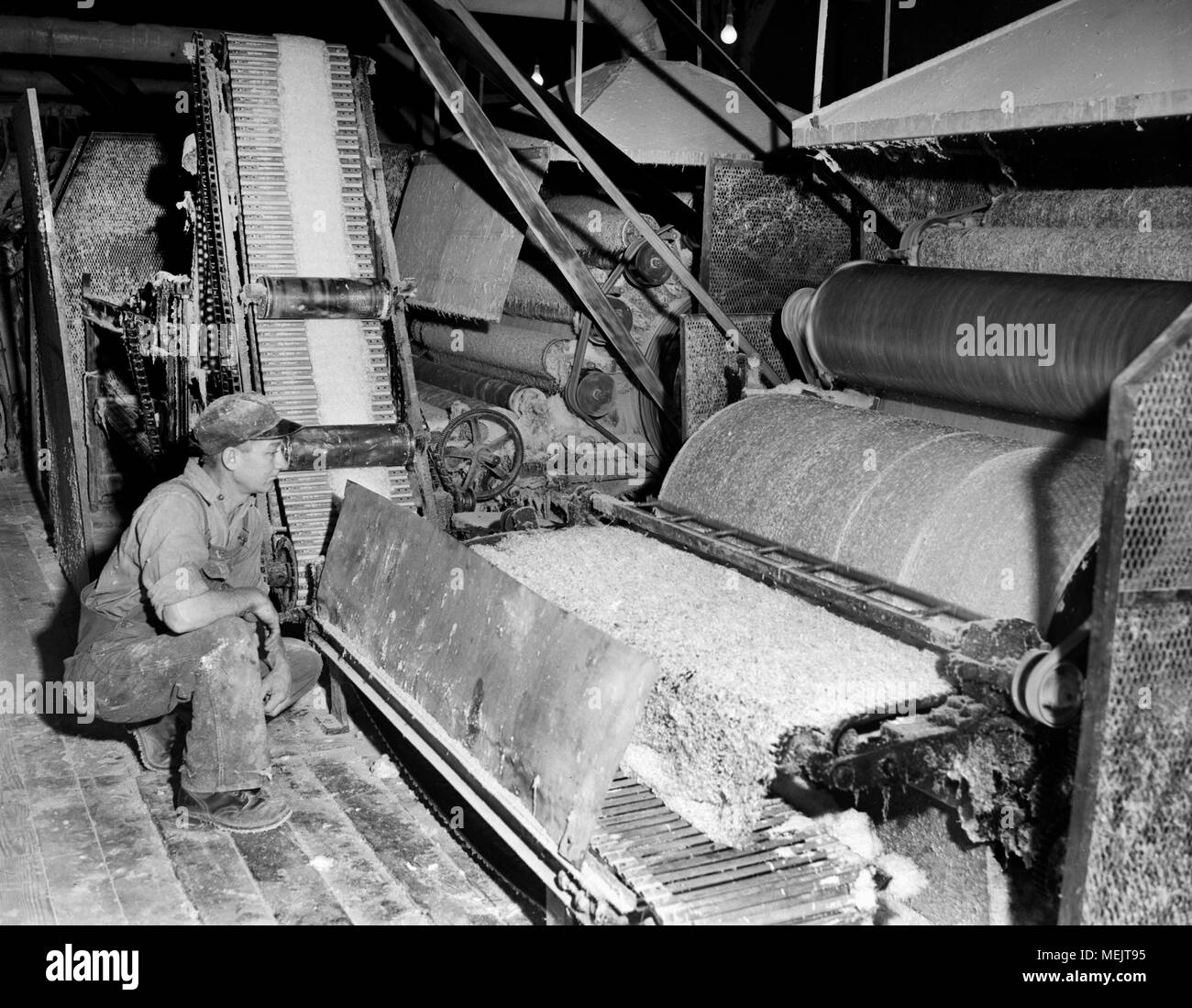 A worker watches an early industrial plastic manufacturing process in a