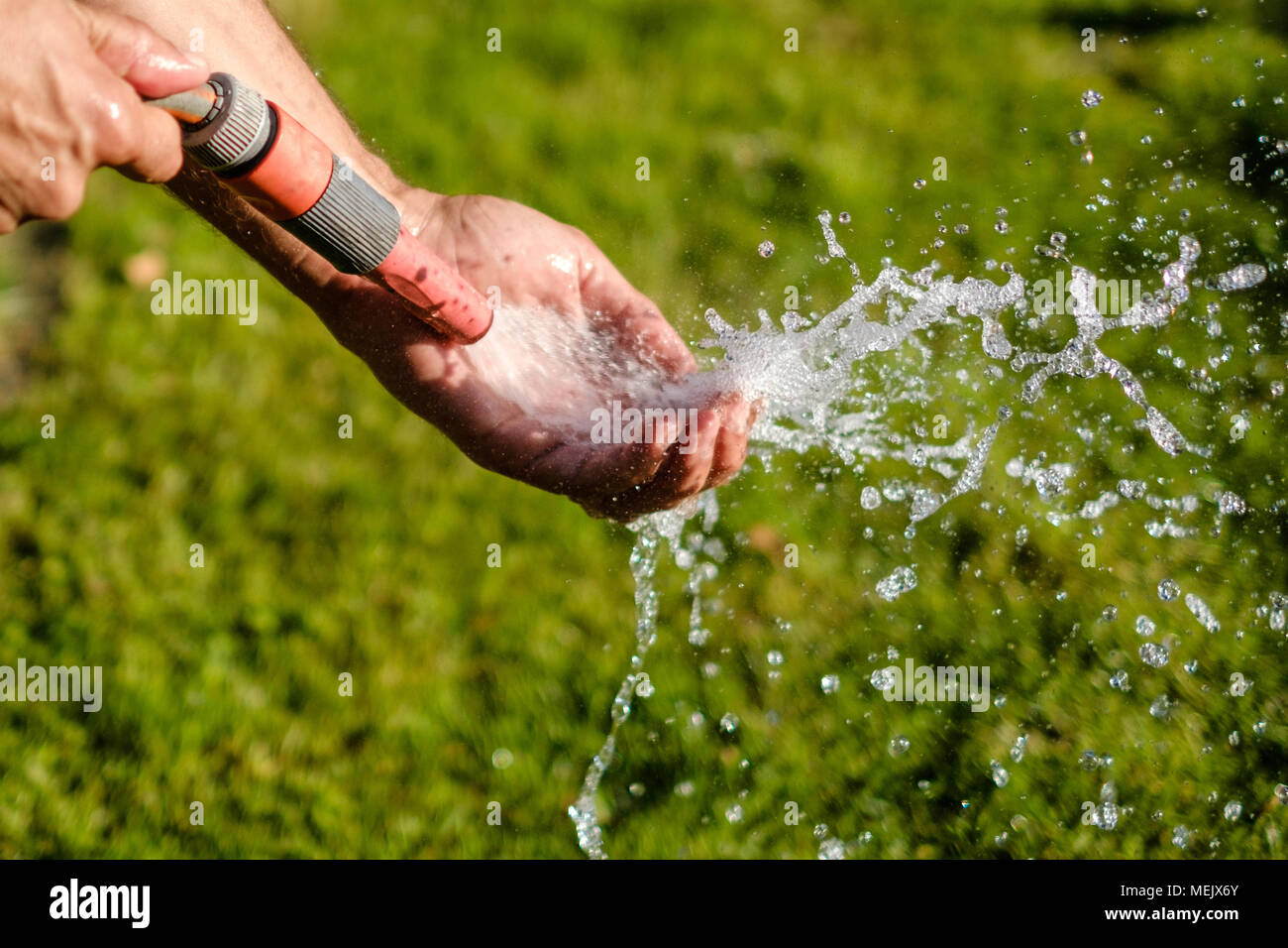 watering garden ,  holding water hose washing hand Stock Photo
