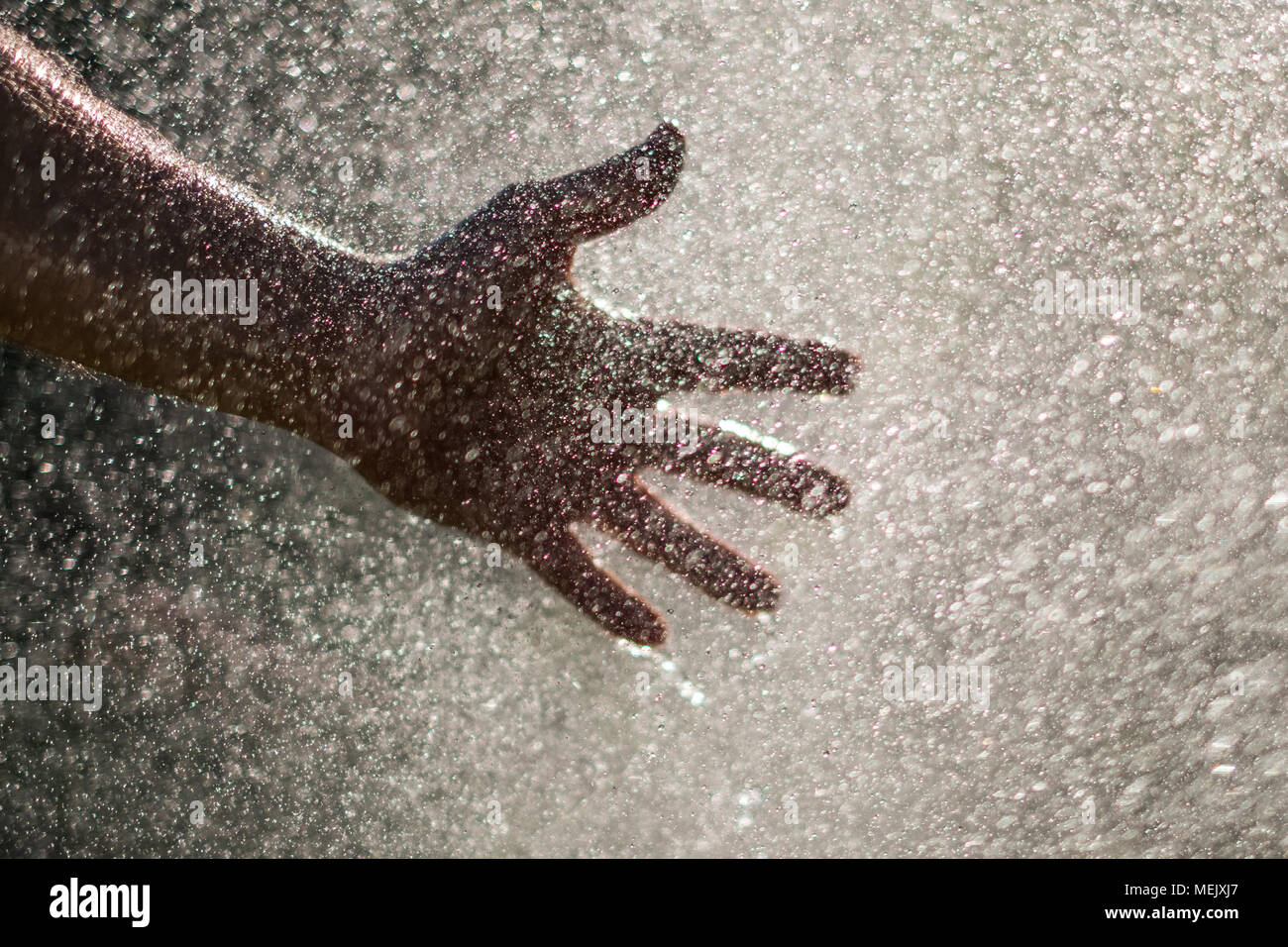 Water drops and hand - holding hand in water splash Stock Photo