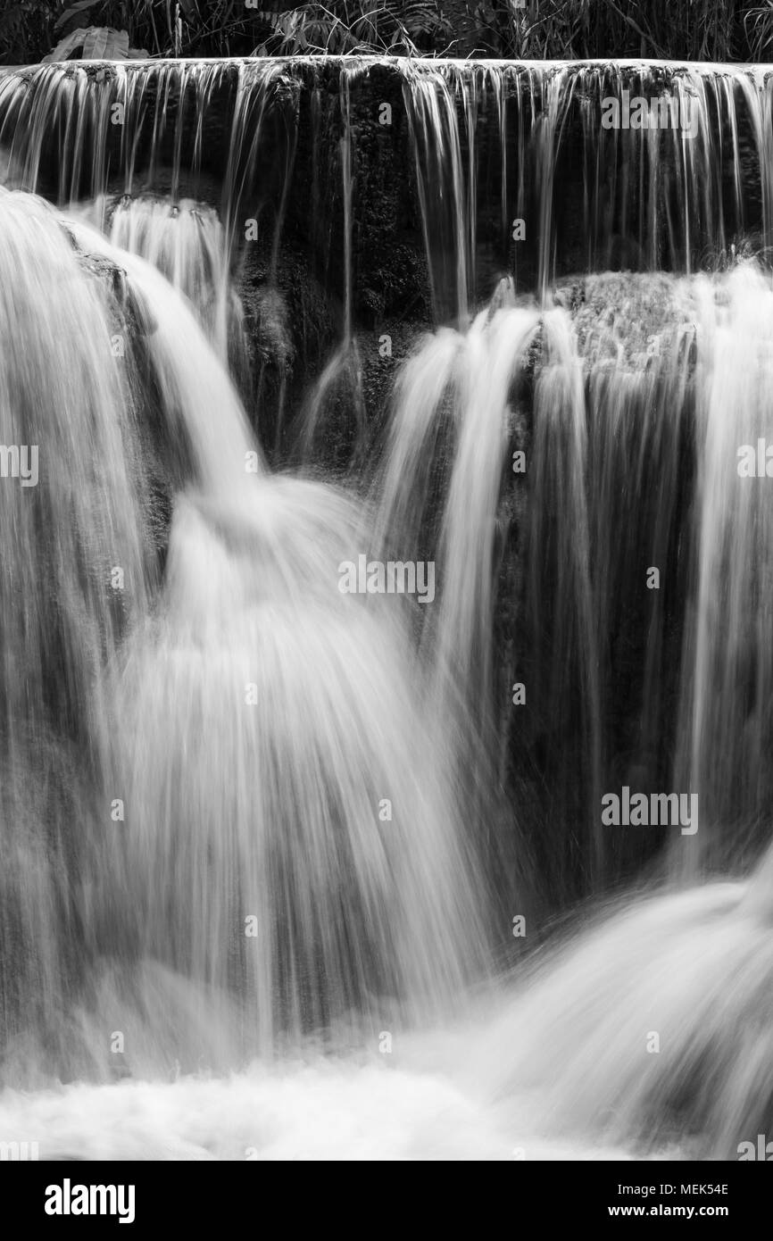 Full frame close-up of a cascade at the Tat Kuang Si Waterfalls near Luang Prabang in Laos. Natural abstract art in black and white. Stock Photo