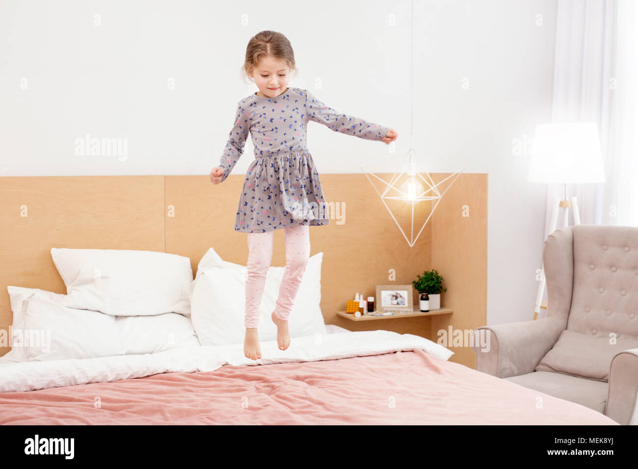 Cheerful girl jumping on bed Stock Photo Alamy