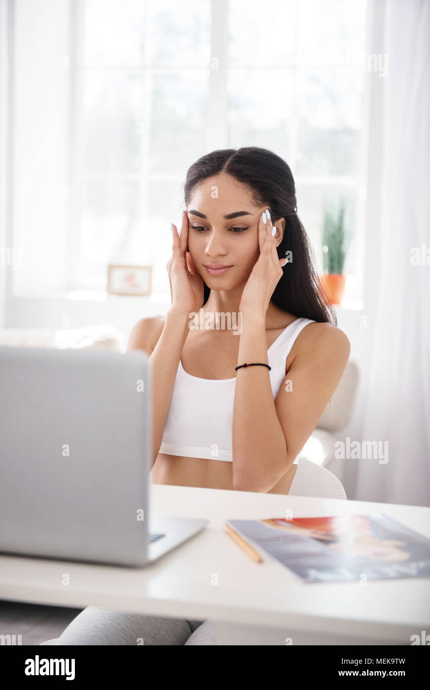 Beautiful woman massaging her temples while sitting at table Stock ...