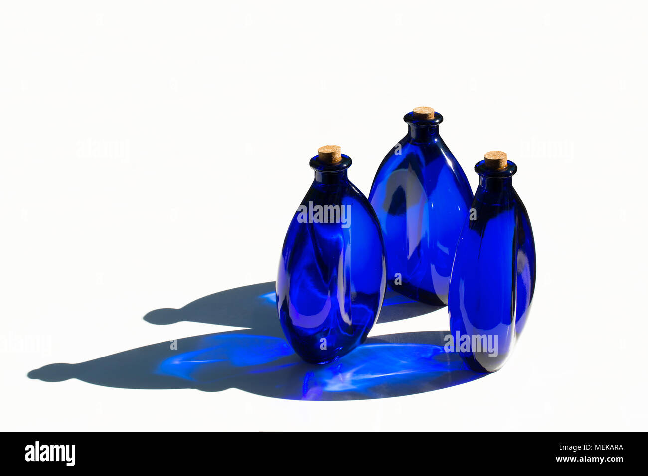 Blue solar water in blue glass bottles sealed with cork stoppers. Isolated on white background. Stock Photo