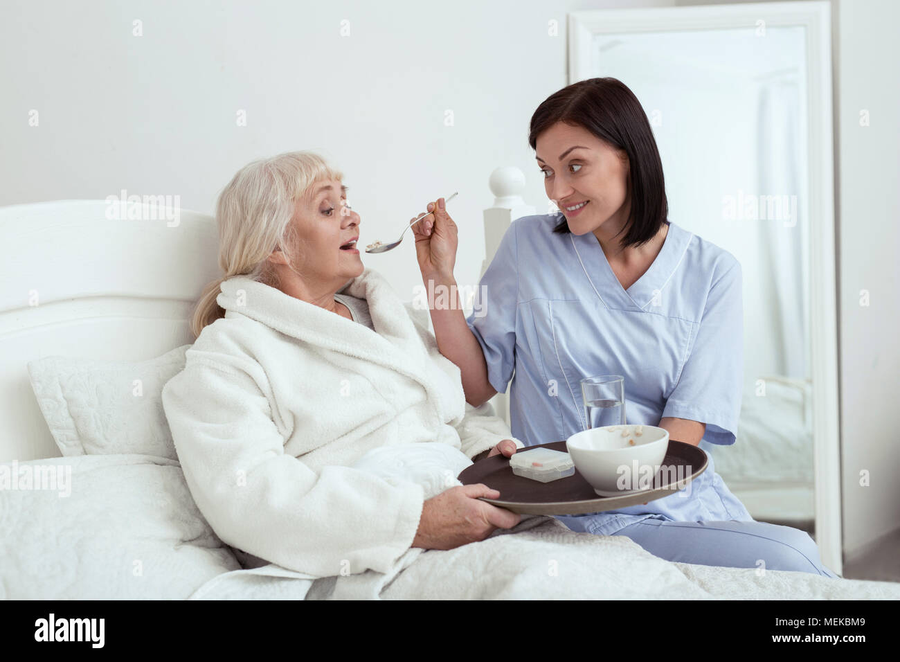 Happy caregiver feeding elder woman Stock Photo Alamy