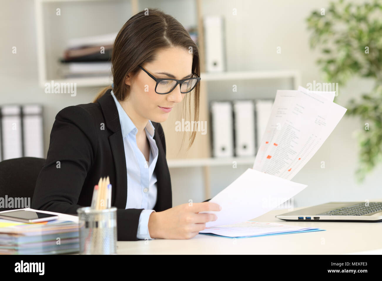 Office worker wearing eyeglasses checking paper documents Stock Photo