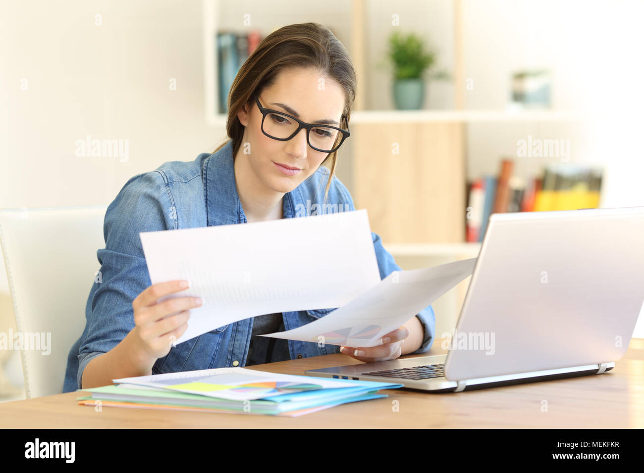 Serious self employed working comparing documents on a table at home Stock Photo