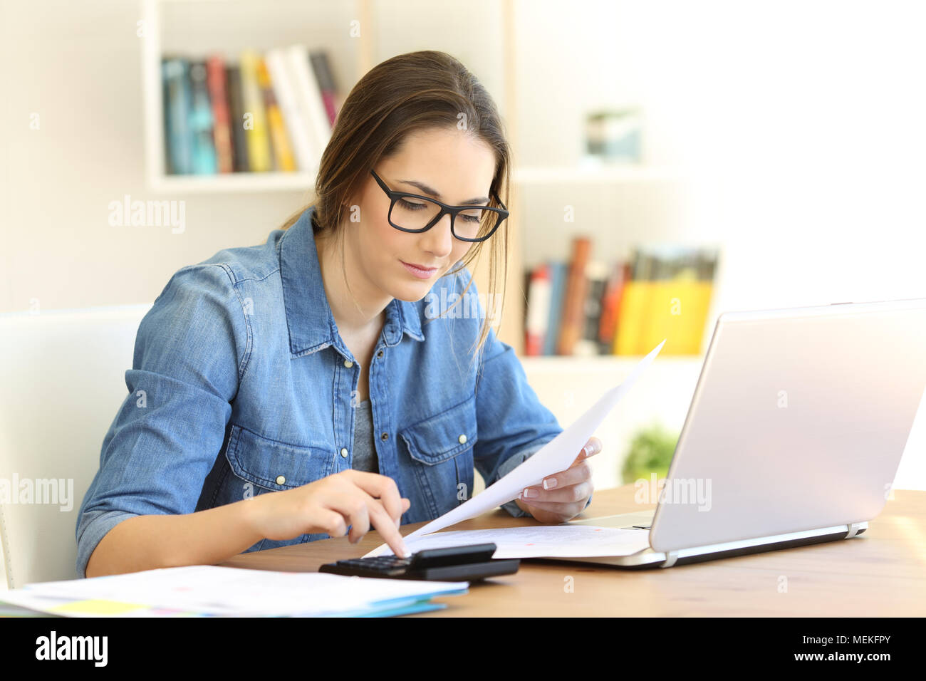 Concentrated woman wearing eyeglasses doing accounting at home Stock Photo