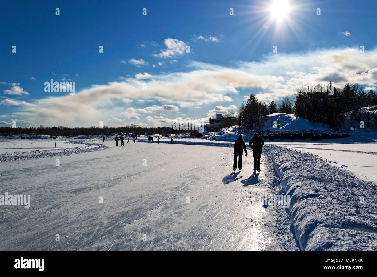 Skaters enjoying a sunny day on the skating path on Ramsey lake, Sudbury, Ontario Stock Photo