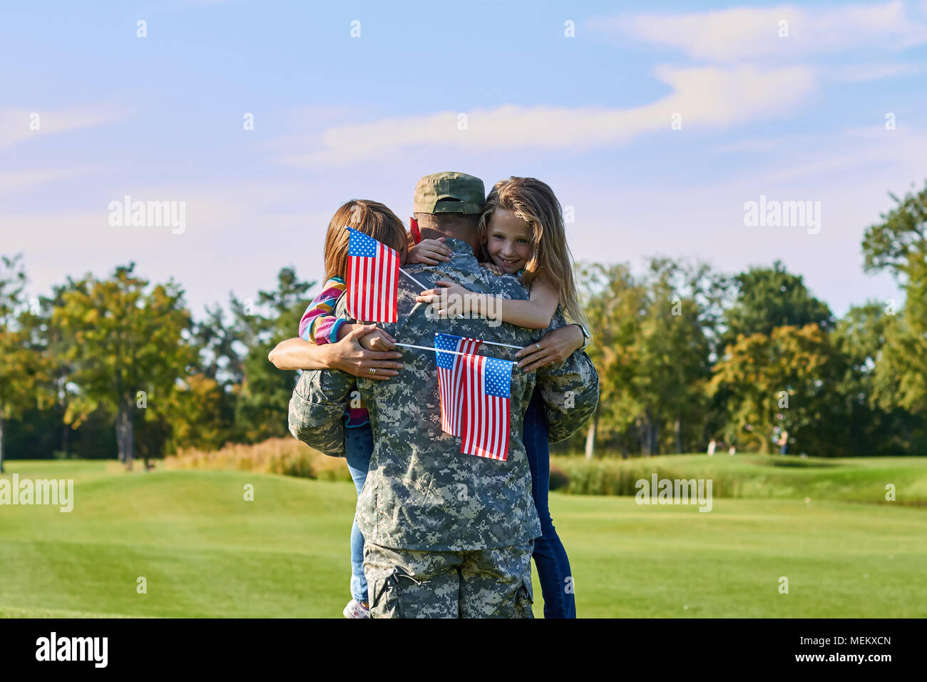 Back view soldier is hugging his family with usa flags. Stock Photo