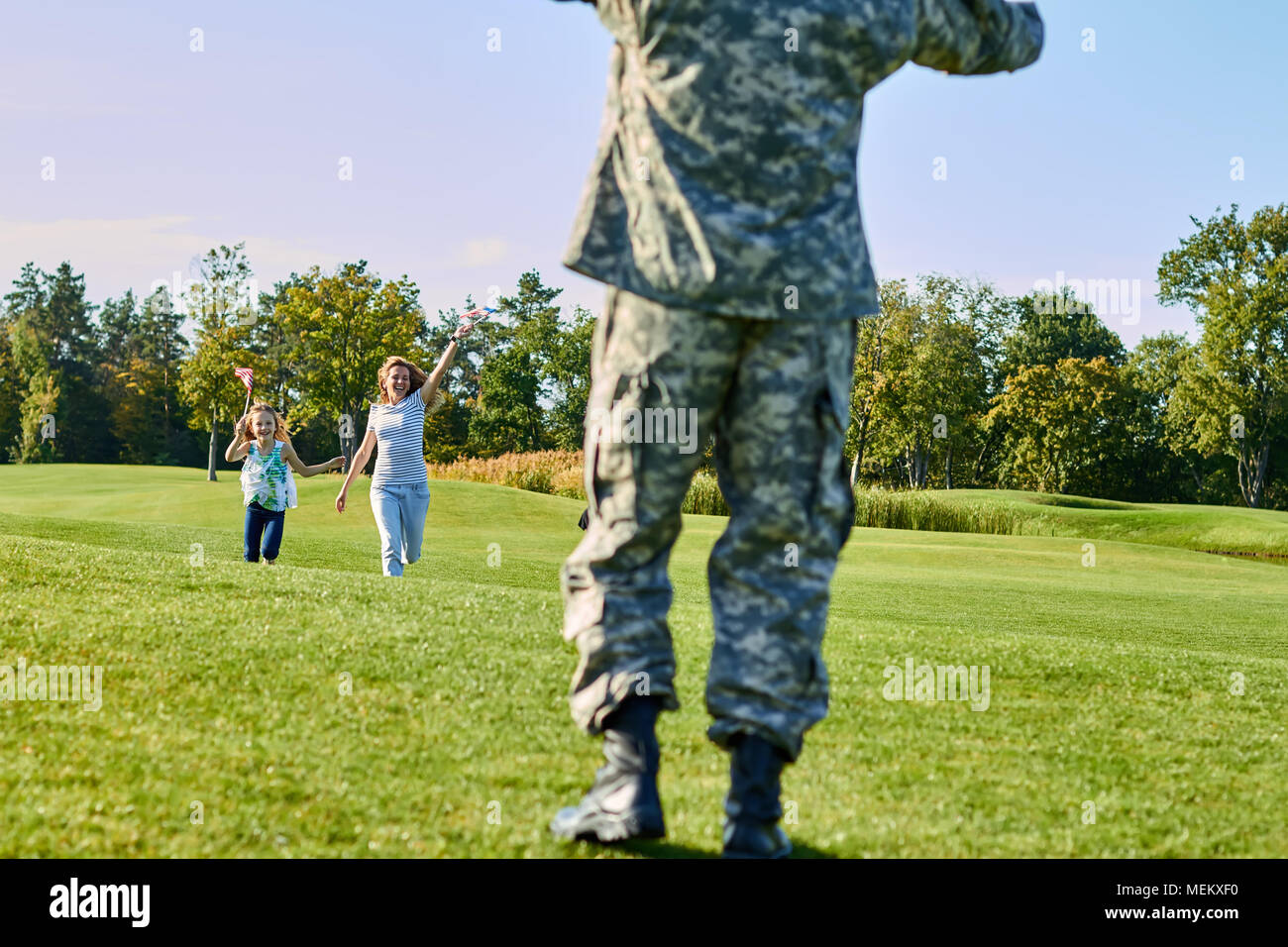 Back view soldier is meeting his family outdoors. Stock Photo