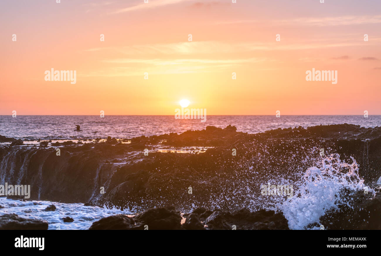 Waves break on pacific coast tide pools during sunset Stock Photo