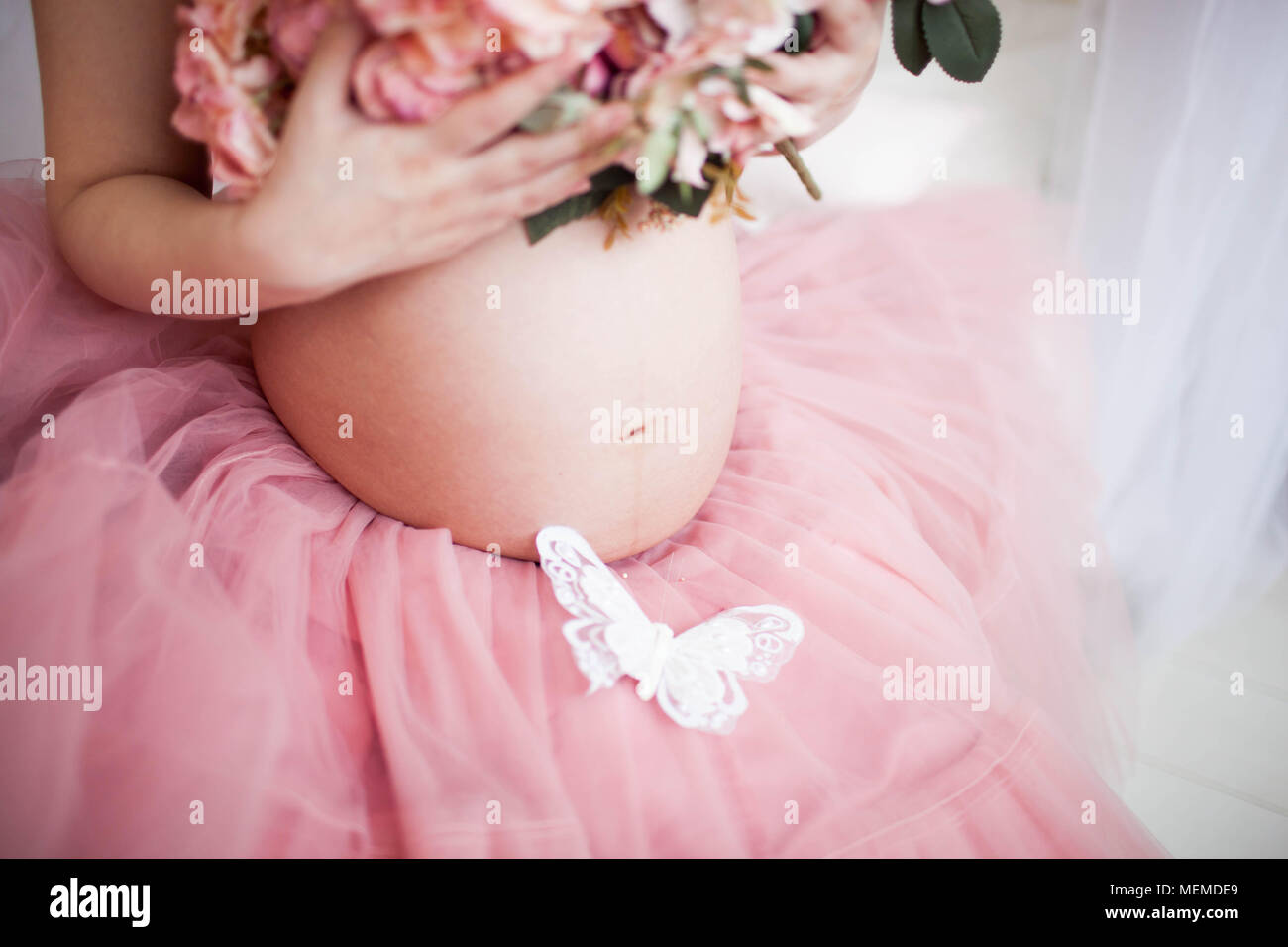 Young pregnant woman holds her hands on her swollen belly. Love concept. Stock Photo