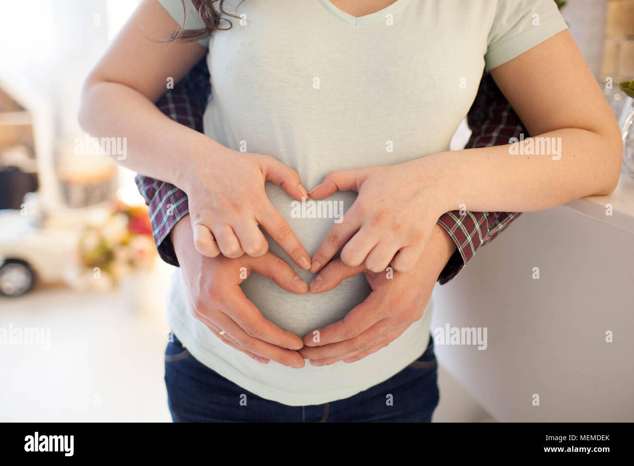 Young pregnant woman holds her hands on her swollen belly. Love concept. Stock Photo