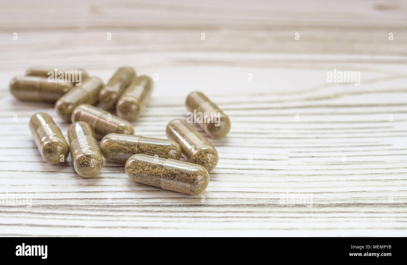 Group of clear CBD Cannabidiol capsules on bright wooden backdrop Stock Photo