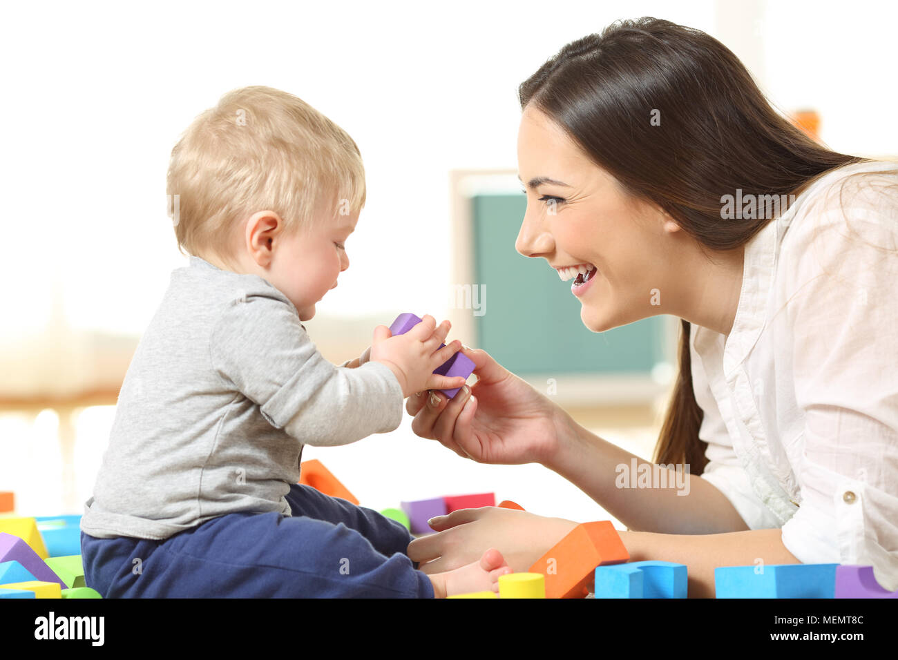 Side view of a happy mother and son playing with toys on the floor Stock Photo
