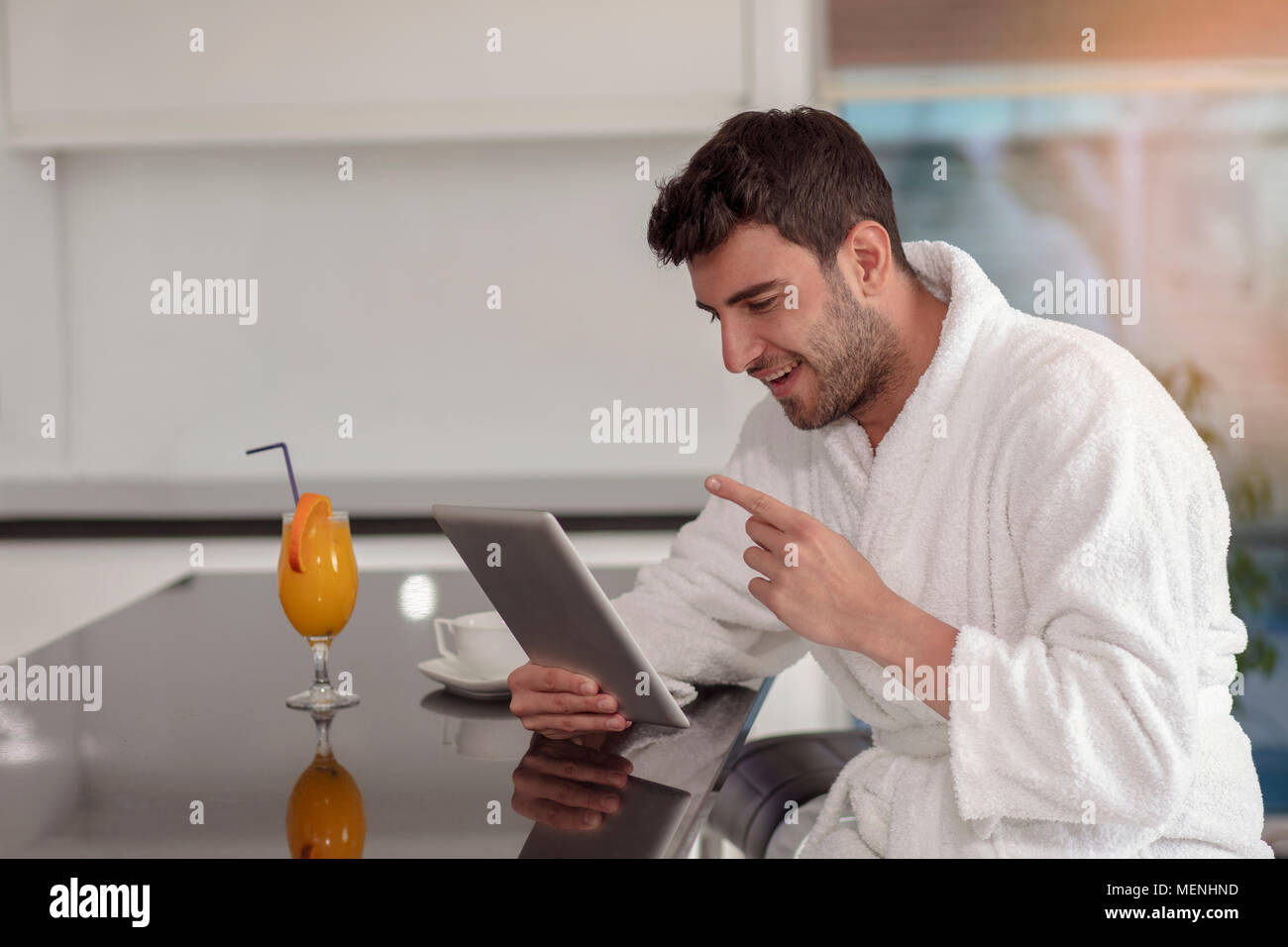 young freelancer in bathrobe working from home using tablet computer Stock Photo