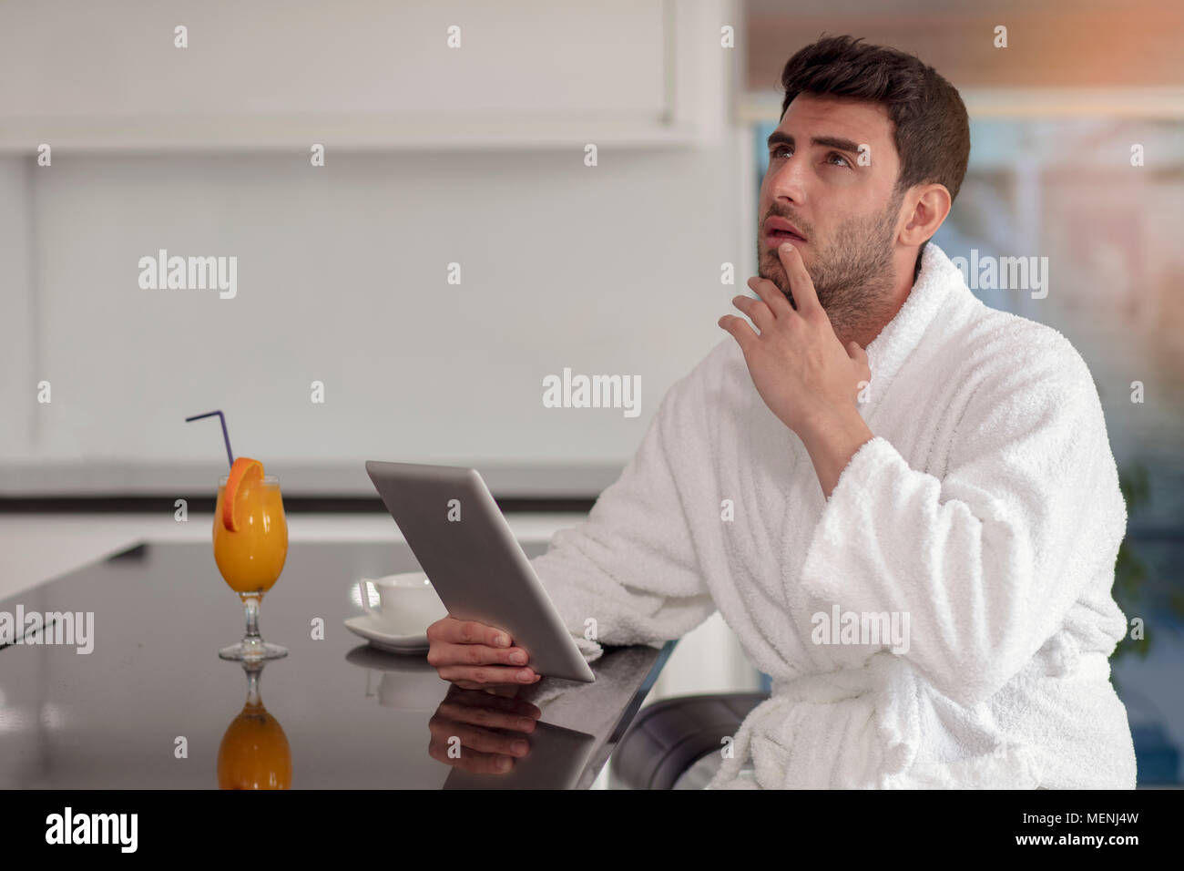 young freelancer in bathrobe working from home using tablet computer Stock Photo