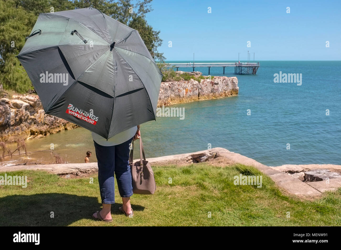 Woman holding a Bunnings Warehouse umbrella and looking at beach goers on  the Nightcliff foreshore near the Nightcliff jetty Darwin Northern  Territory Stock Photo - Alamy