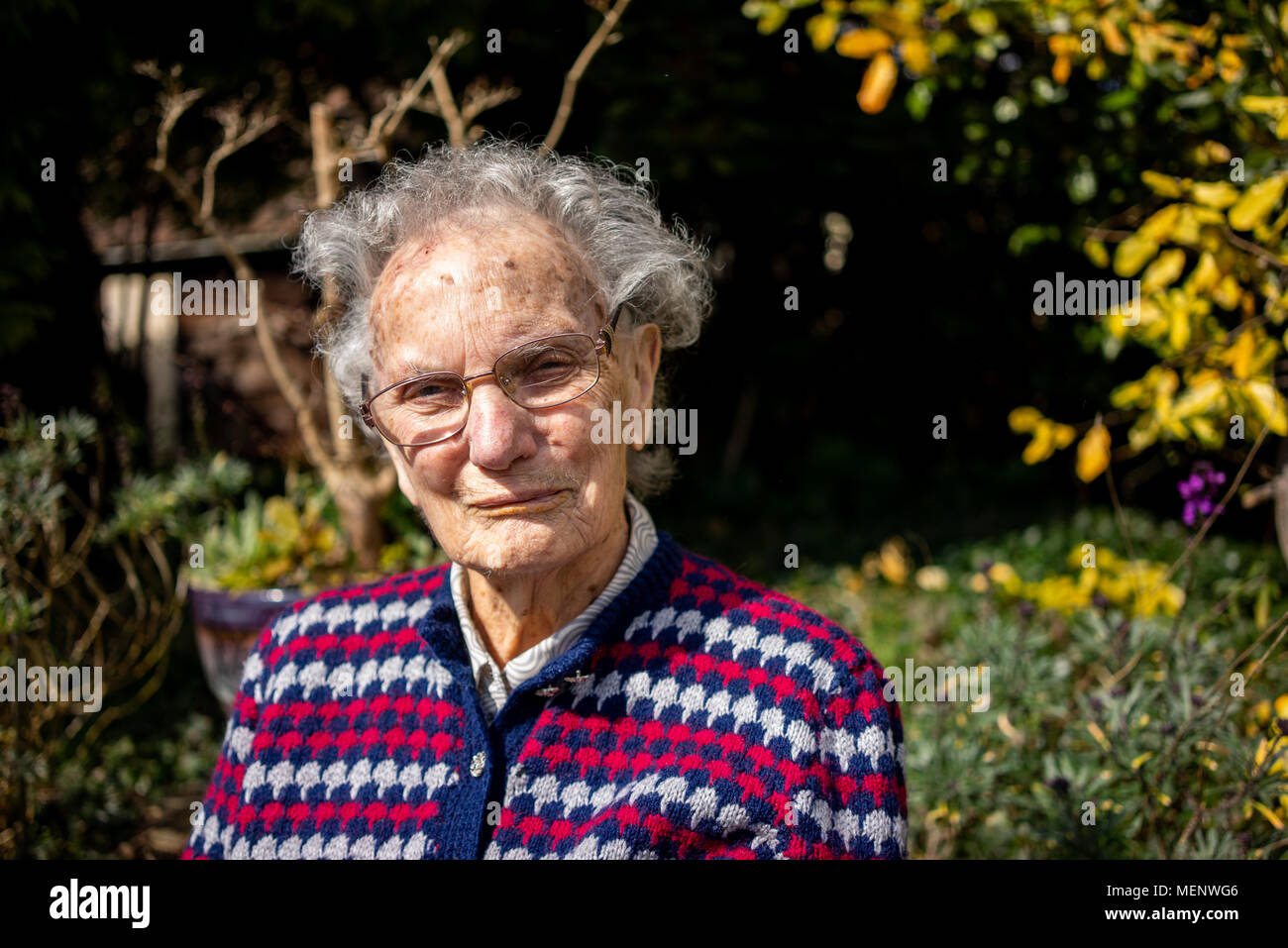 Elderly woman sitting in her garden in West Sussex England Stock Photo