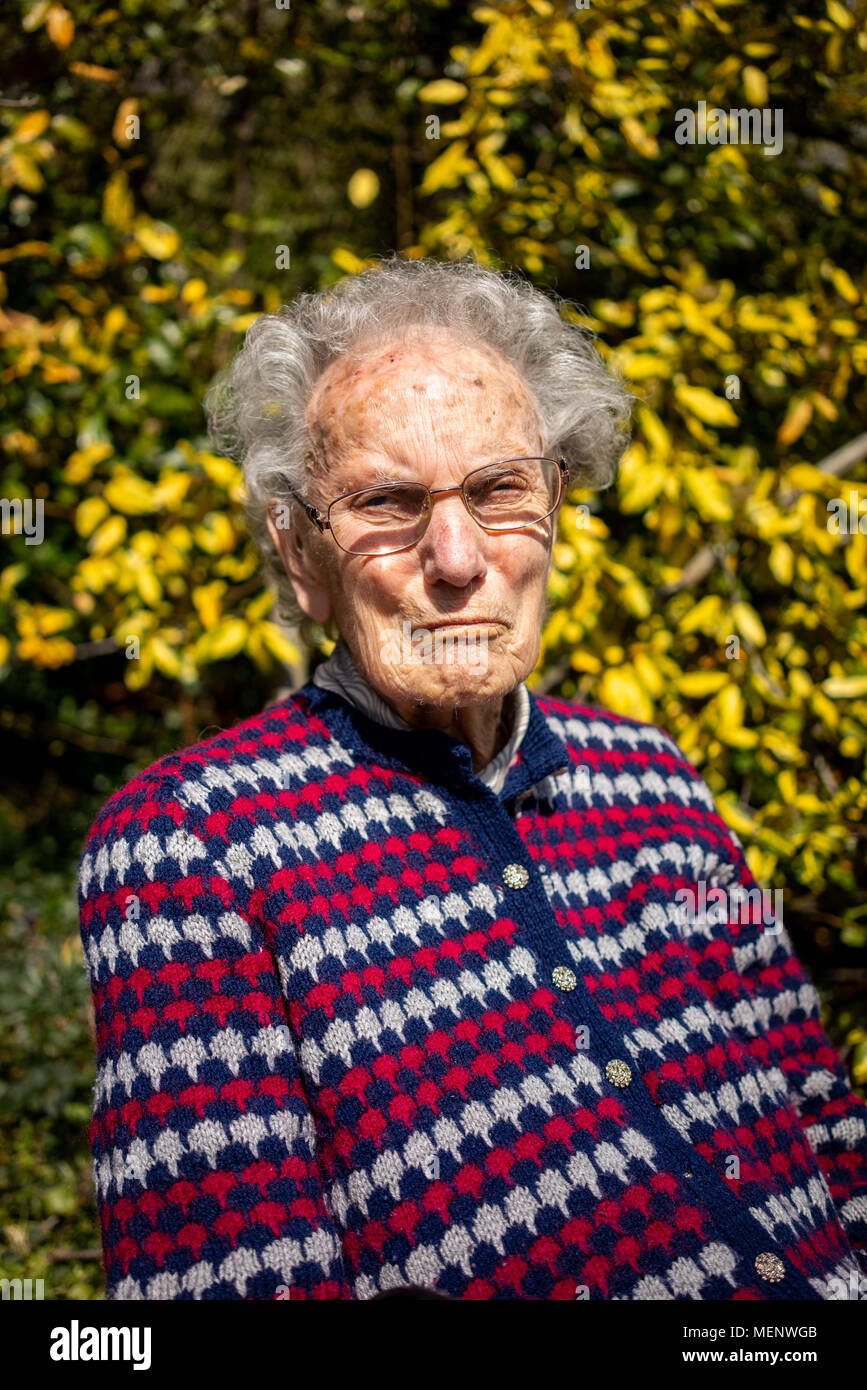 elderly-woman-sitting-in-her-garden-in-west-sus-england-stock-photo
