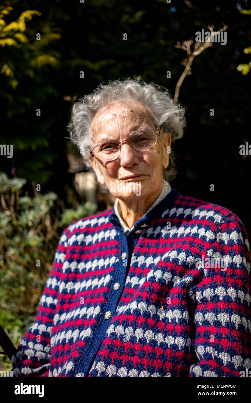 Elderly woman sitting in her garden in West Sussex England Stock Photo