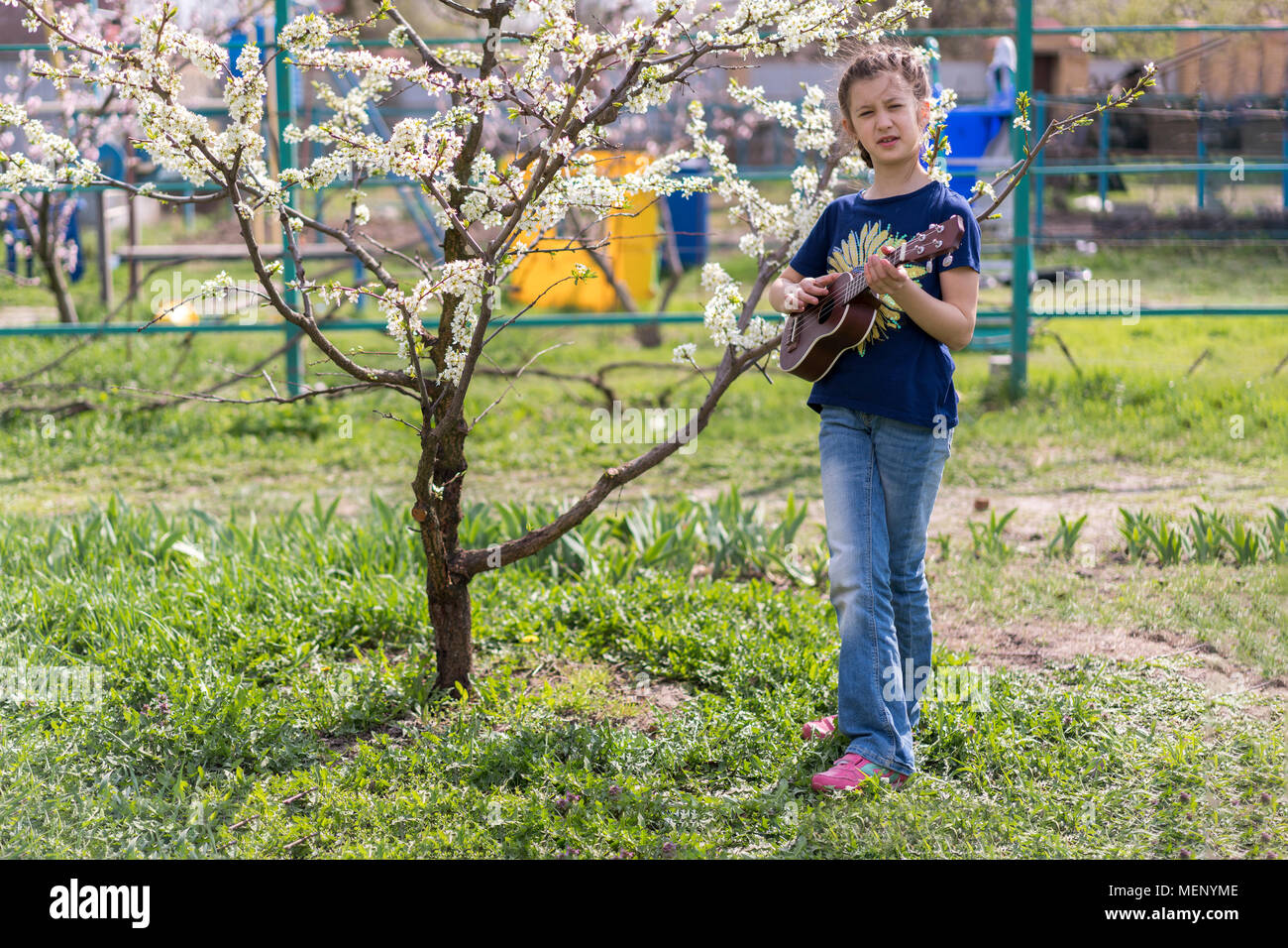A little girl playing ukulele in the garden Stock Photo Alamy
