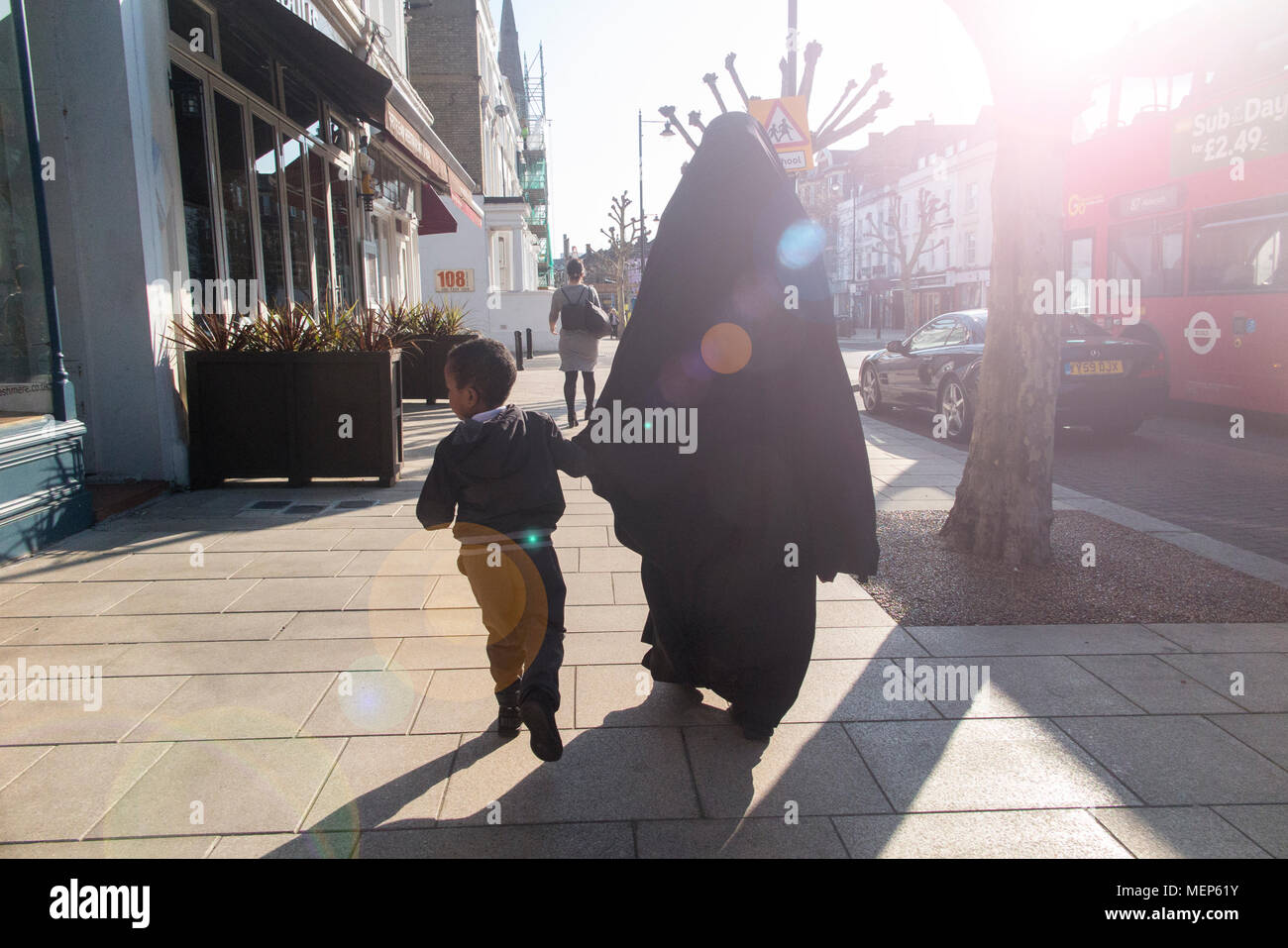 A veiled muslim mother with her child walking along a London street Stock Photo