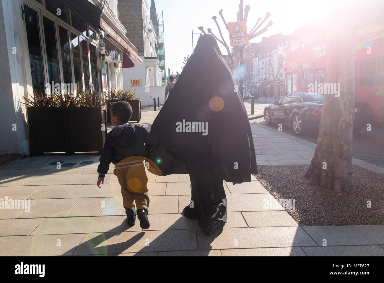 A veiled muslim mother with her child walking along a London street Stock Photo