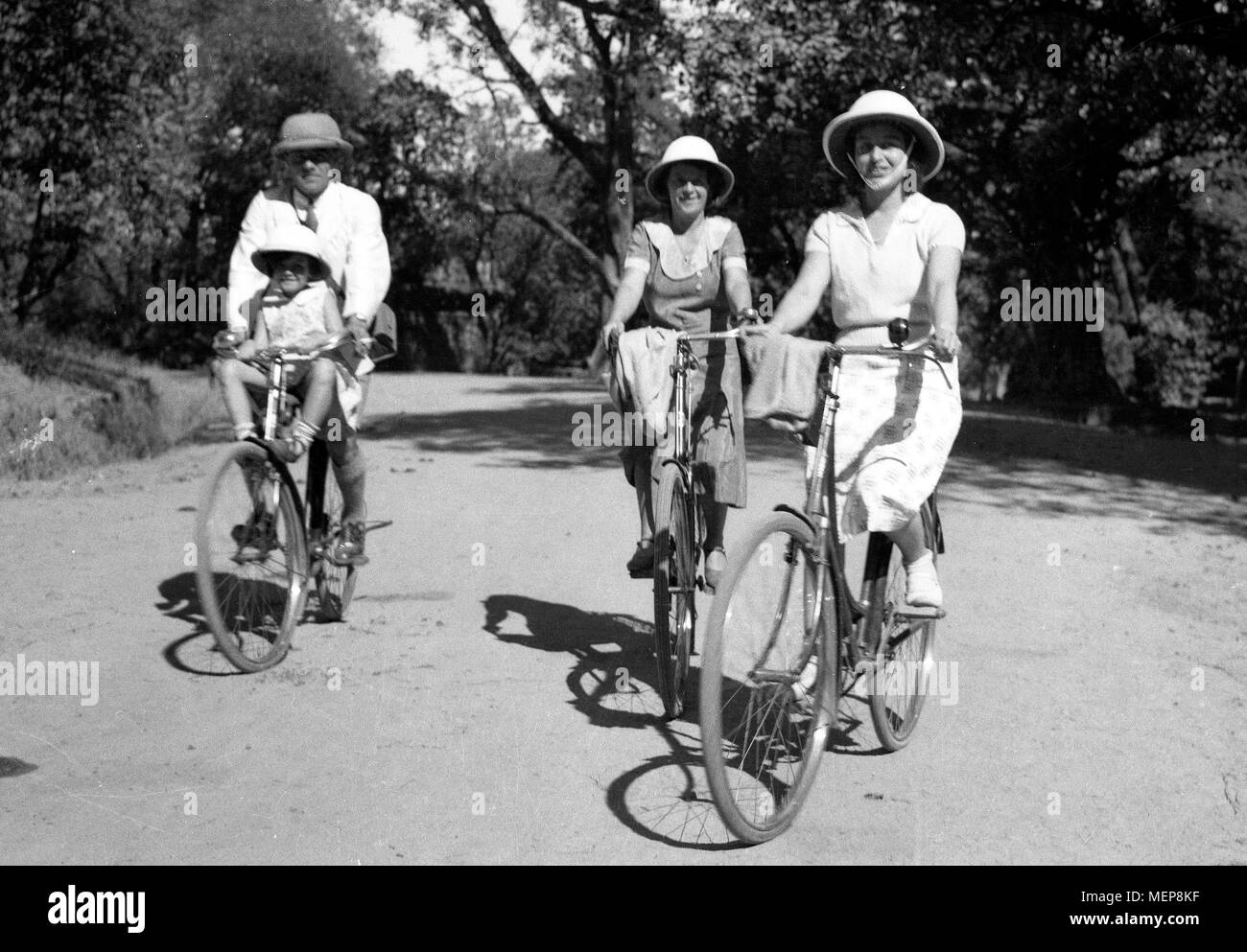 Colonial days! Family cycling in India 1932 wearing safari hats Stock Photo