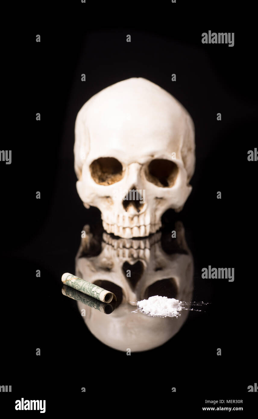 cocaine or other illegal drugs that are sniffed by means of a tube and Skull, isolated on black glossy background Stock Photo