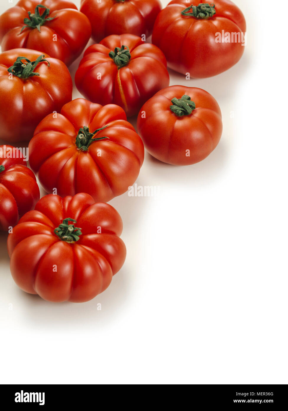 Photo of a table top with Marmande tomatoes over a white background. Stock Photo