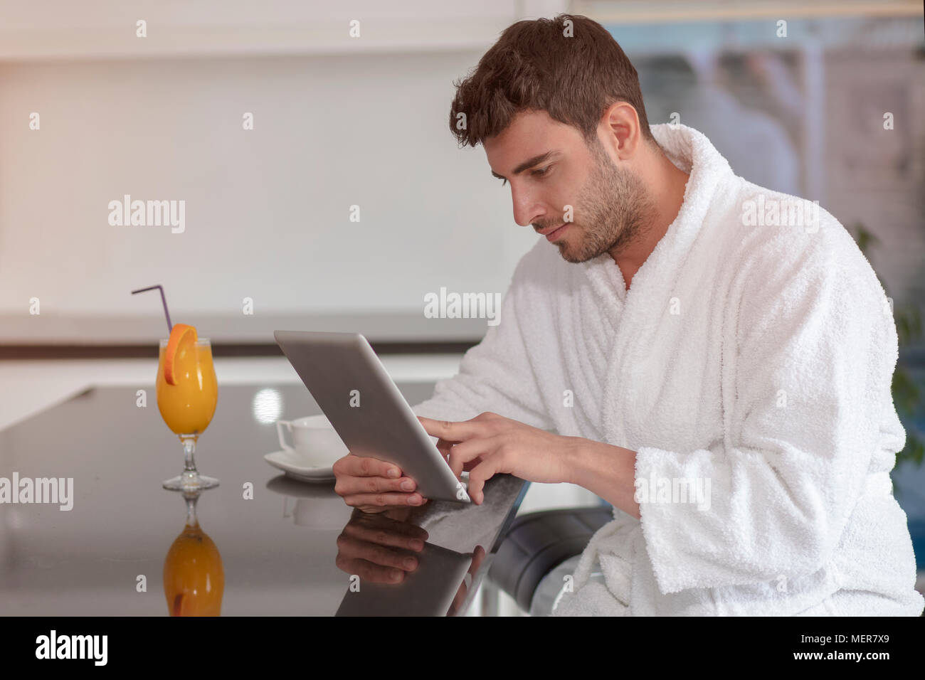 young freelancer in bathrobe working from home using tablet computer Stock Photo