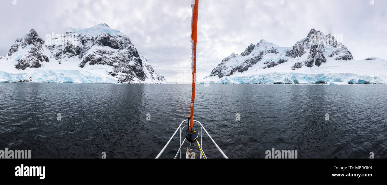 Panoramic view of sailboat bow or prow in the famous Lemaire Channel in the Antarctic Peninsula. Surrounded by mountains and glaciers while sailing in Stock Photo