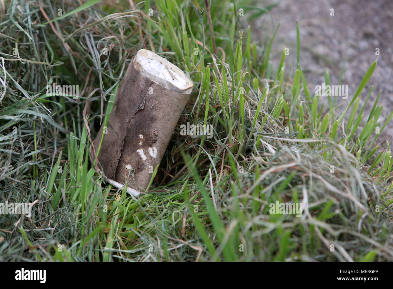 An old single use coffee cup pictured in the grass by the side of a road in Chichester, West Sussex, UK. Stock Photo