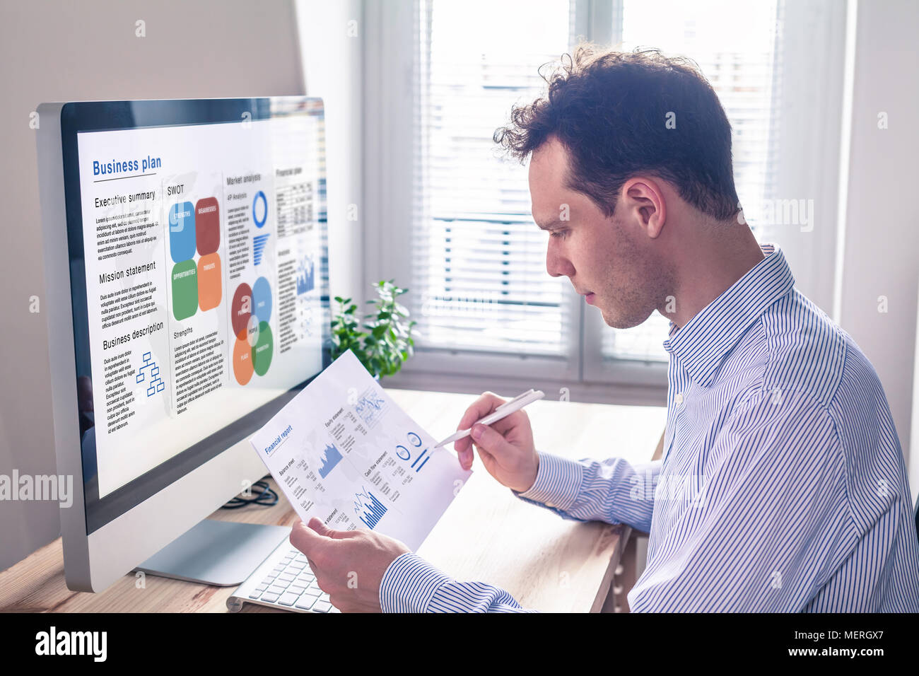 Businessman working on a business plan on computer screen in office with executive summary, mission statement, SWOT, market analysis, and financial re Stock Photo