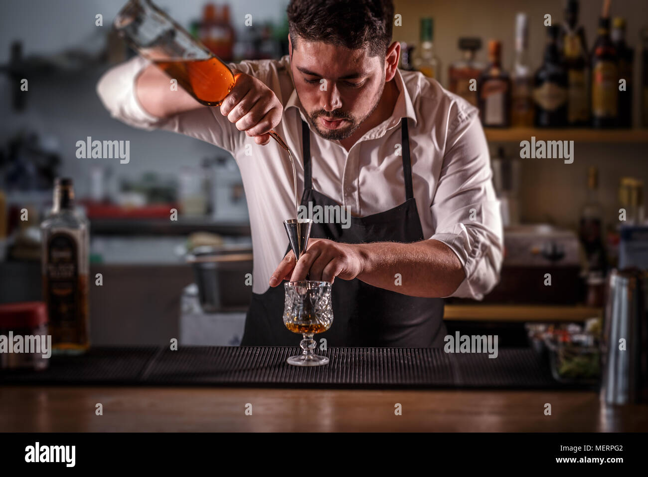 Barman pouring mixture into a jigger to prepare a cocktail Stock Photo