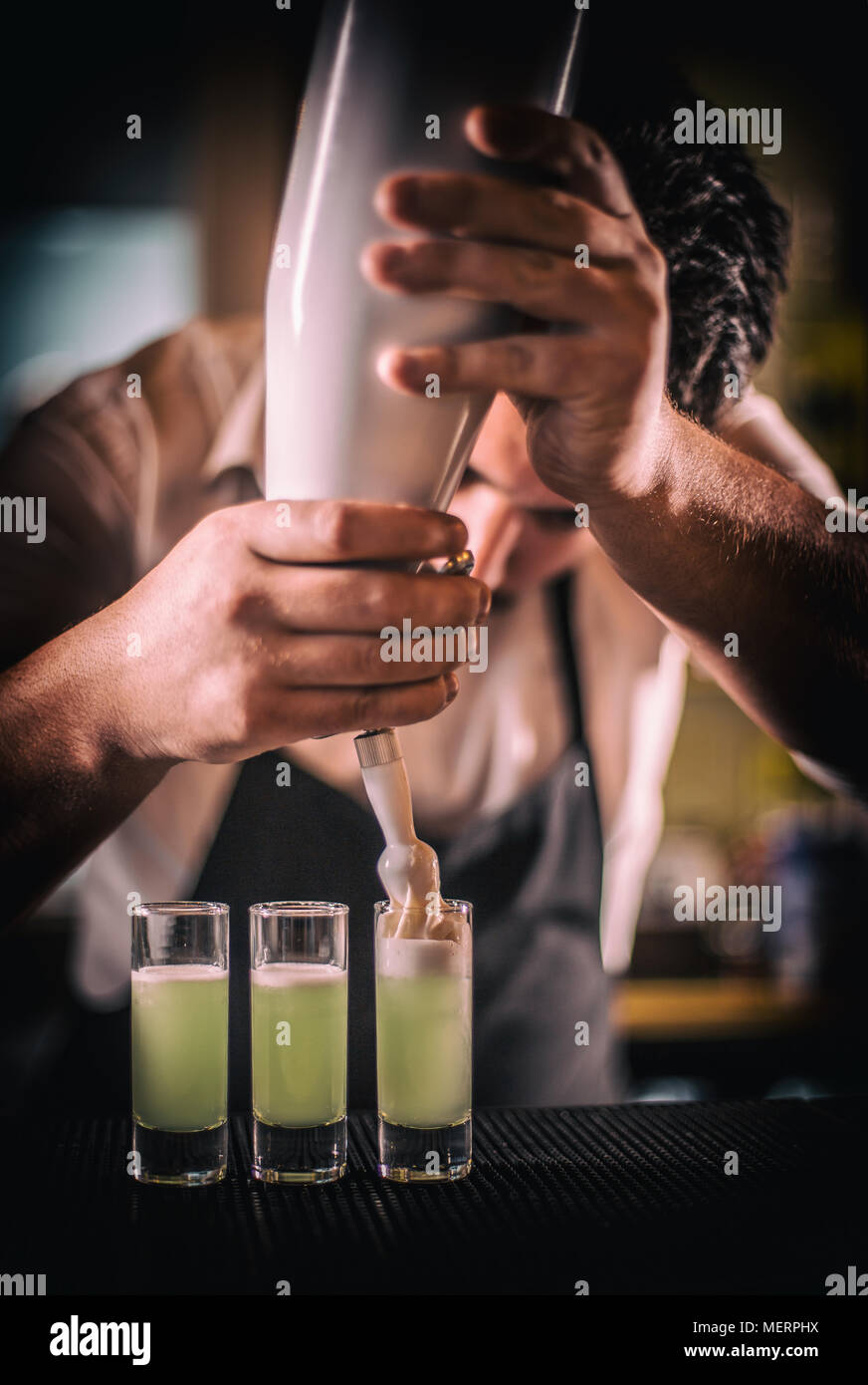 Bartender preparing shot drinks, decorated with hazelnut whipped cream Stock Photo