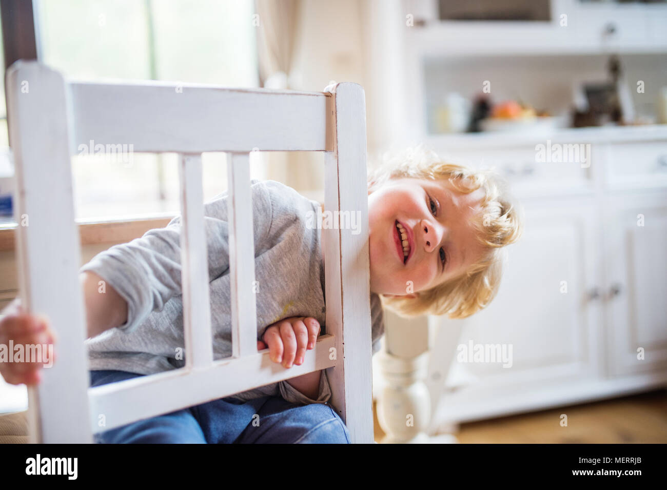 A toddler boy sitting on the chair at home. Stock Photo