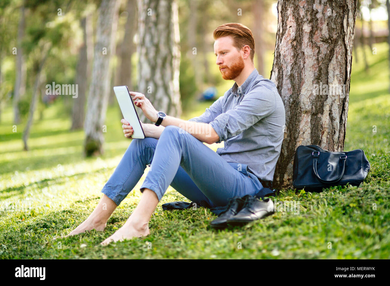 Businessman using tablet in park Stock Photo