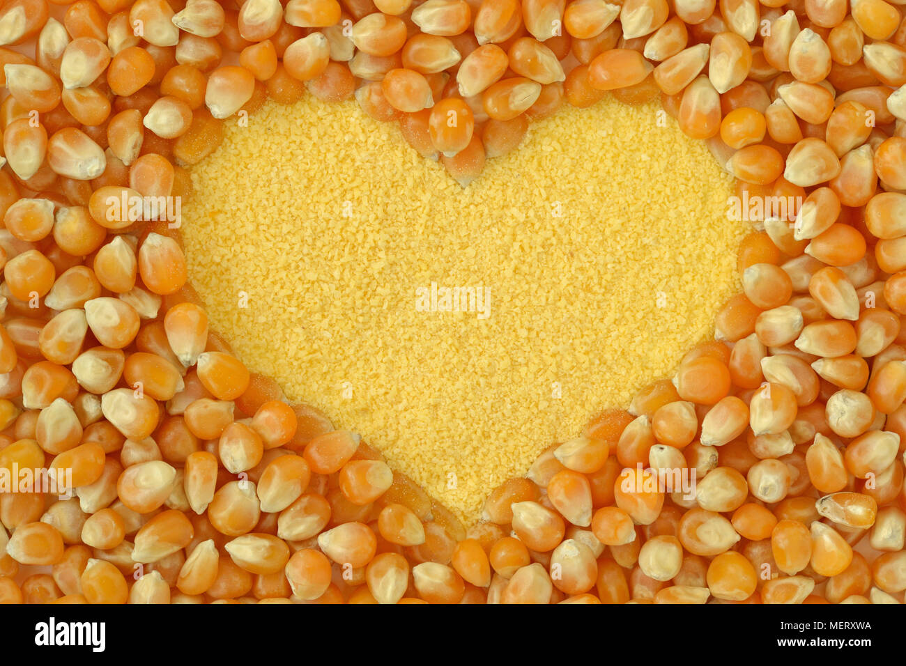 Maize flour heart with corn kernels background Stock Photo