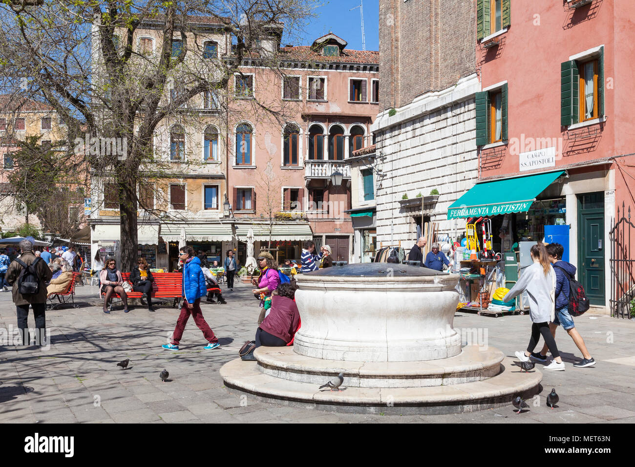 The ancient well head or pozzo in Campo Santi Apostoli, Cannaregio, Venice, Veneto, Italy with people enjoying a sunny spring day Stock Photo
