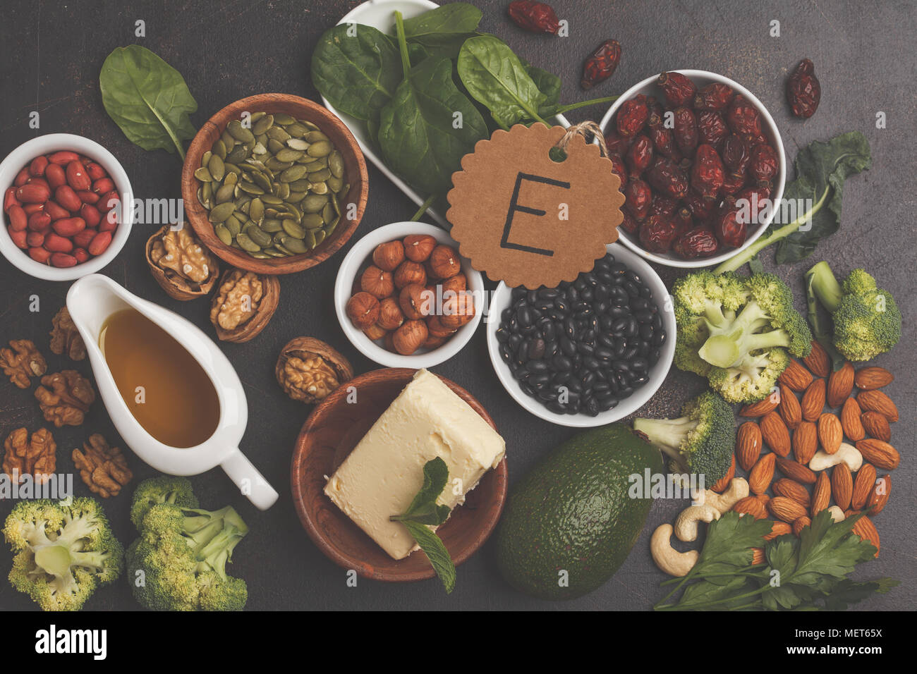 Healthy food nutrition dieting concept. Assortment of high vitamin E sources. Oil, nuts, avocado, butter, healthy fats, dark background Stock Photo