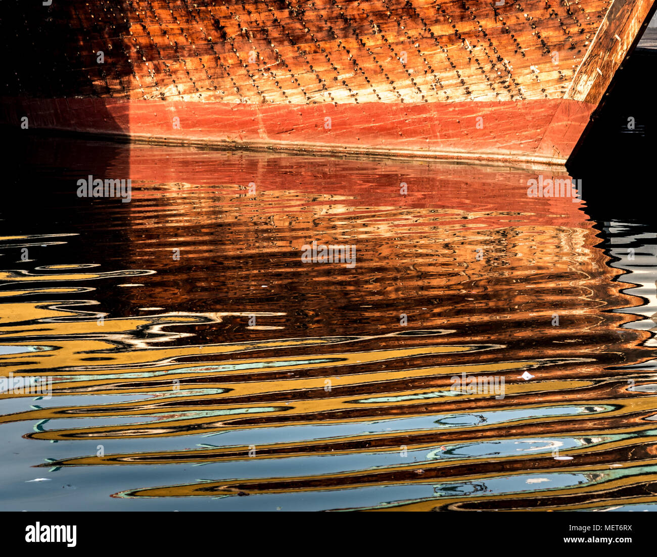 Reflectin of a wooden boat in water creating beautiful pattern. Stock Photo