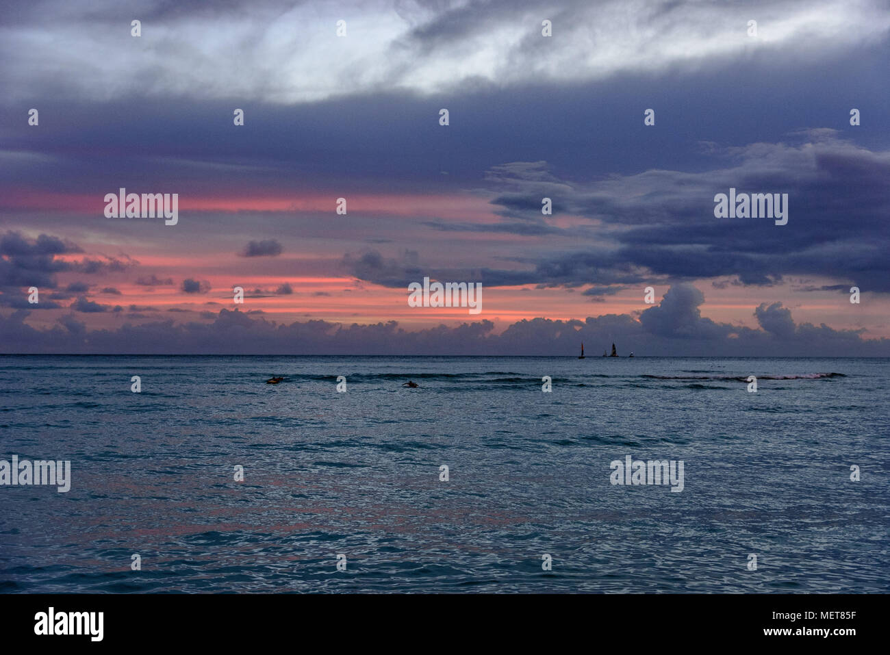 Sailboats on the far horizon at twilight seen from Waikiki Beach, Hawaii Stock Photo