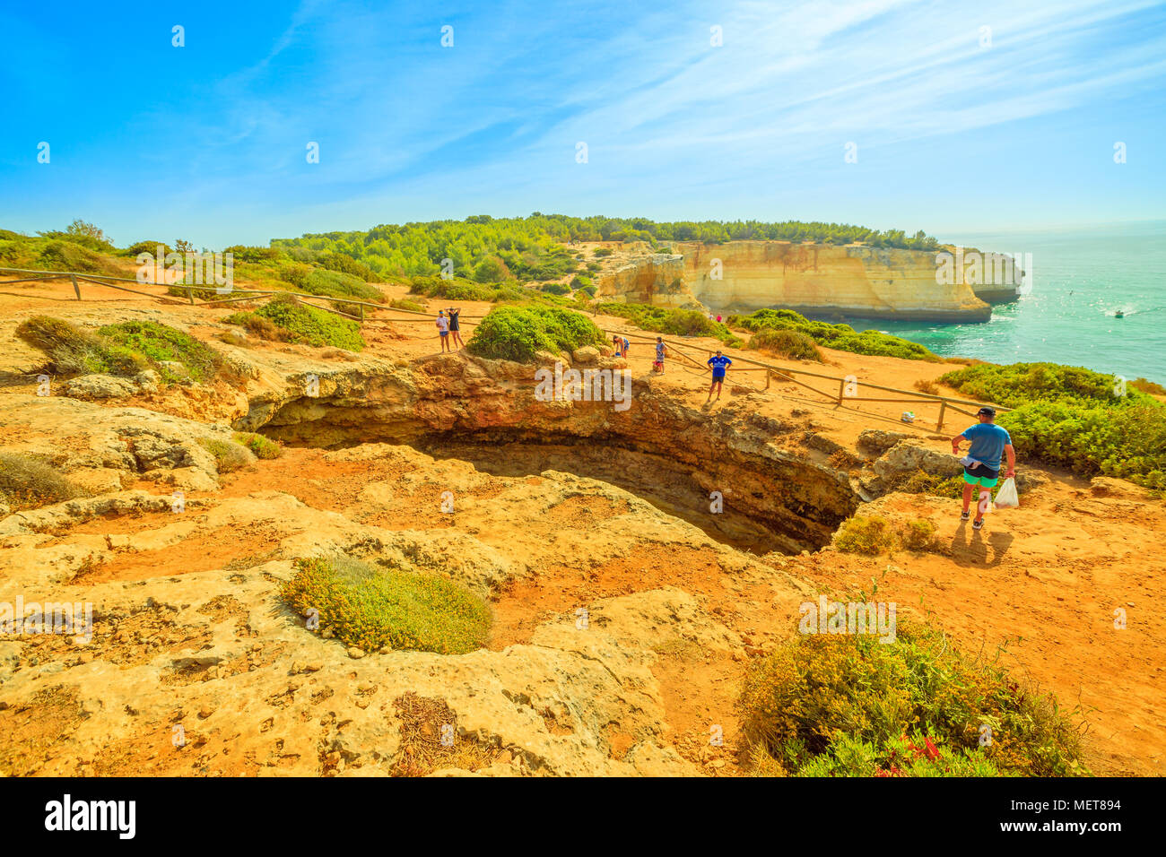 Benagil, Portugal - August 23, 2017: Benagil Cave seen from the top of rocky cliff in Algarve coast, Lagoa, Portugal. People watching the impressive sea caves from above. Summer holidays. Stock Photo