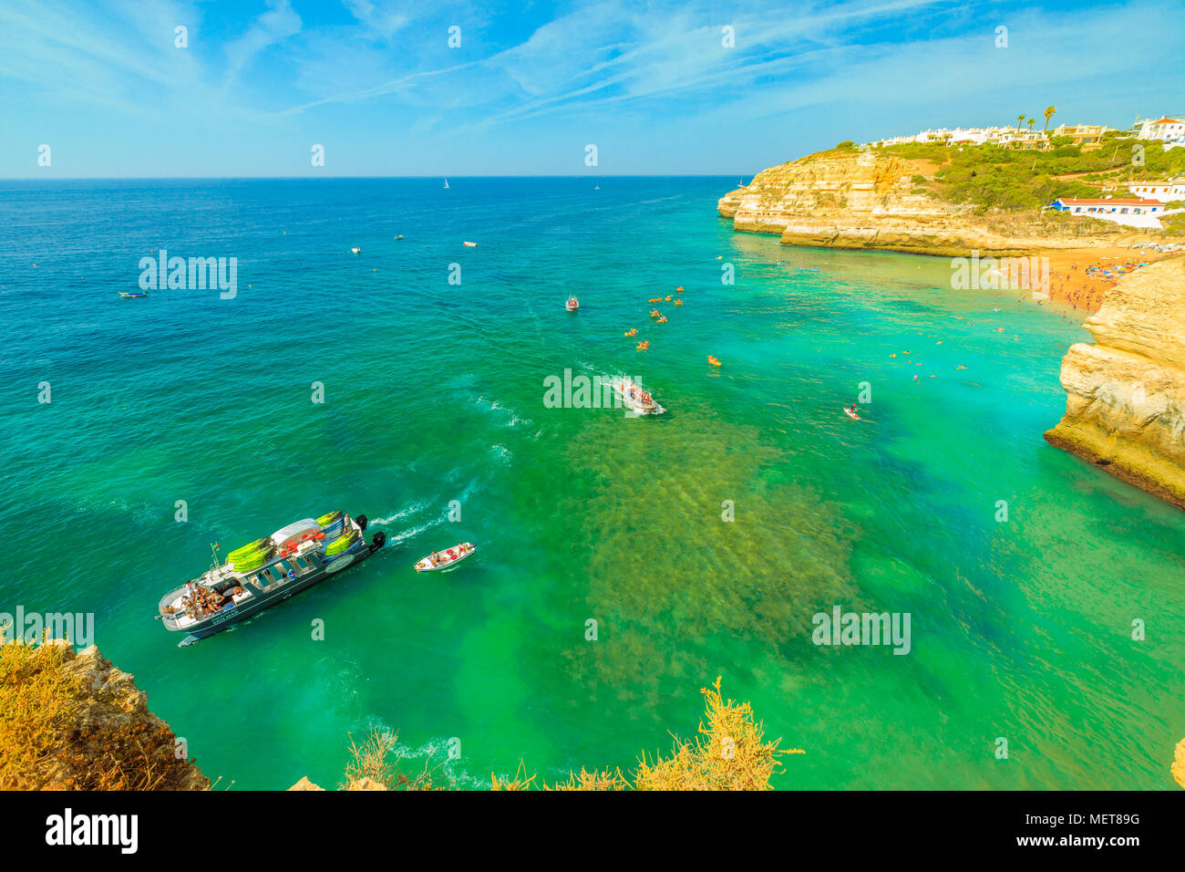 Benagil, Portugal - August 23, 2017: aerial view from promontory in Algarge Coast of boats and kayaking tour to famous sea cave Algar de Benagil. Praia de Benagil in the distance. Turquoise waters. Stock Photo