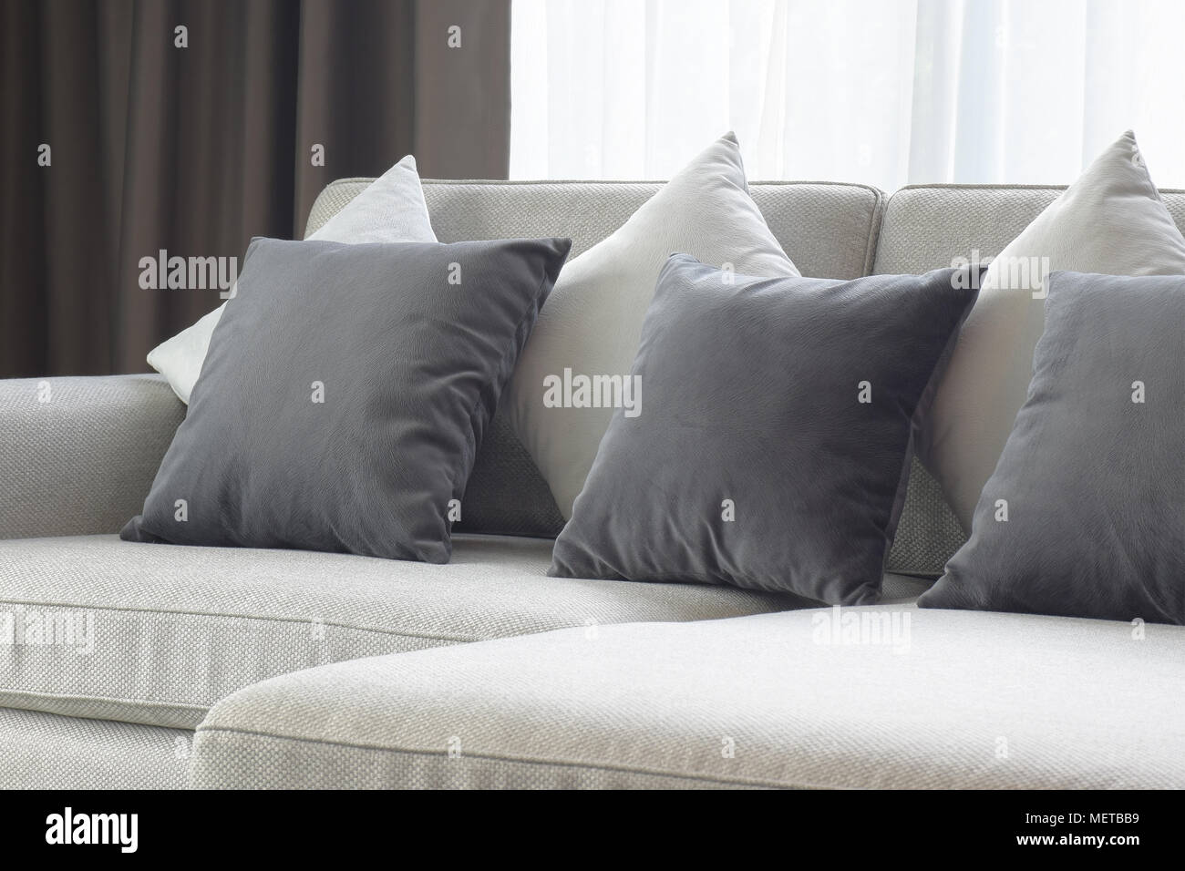 White and gray pillows setting on beige couch in living room Stock Photo Alamy