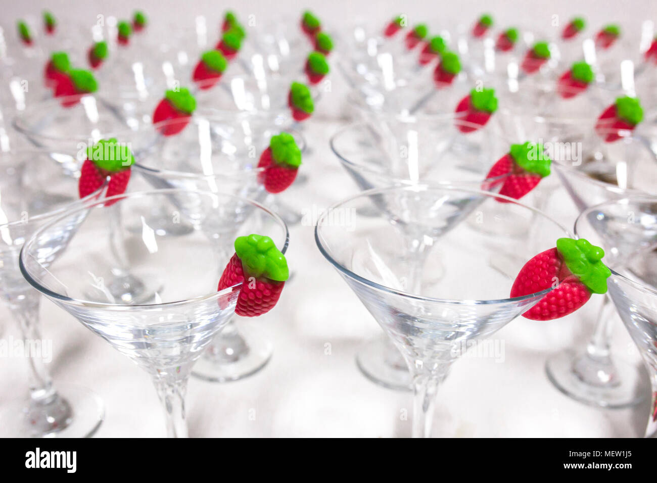 Empty sorbet cocktail glasses with gummy strawberry ready on edge. Closeup Stock Photo