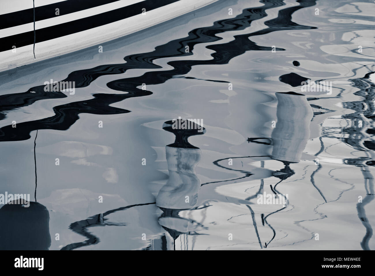 Reflections of a boat moored in a marina in the water of the harbor ...